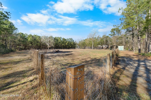 view of yard featuring fence, a rural view, and a wooded view
