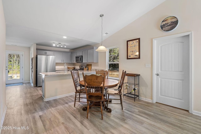 dining room featuring vaulted ceiling, light hardwood / wood-style floors, a wealth of natural light, and sink