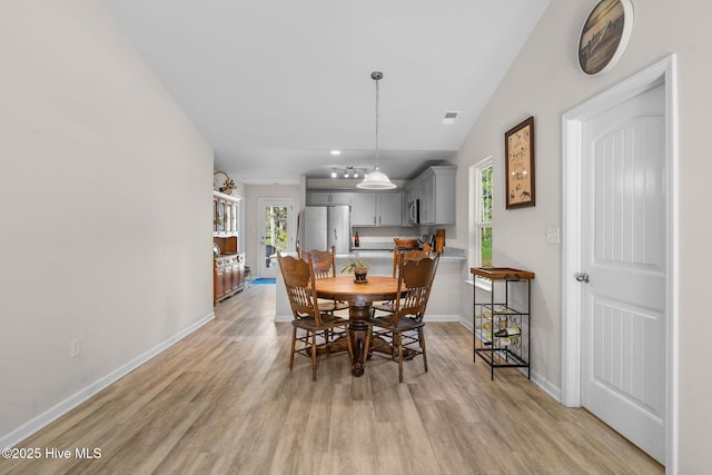 dining room featuring baseboards, vaulted ceiling, and light wood finished floors