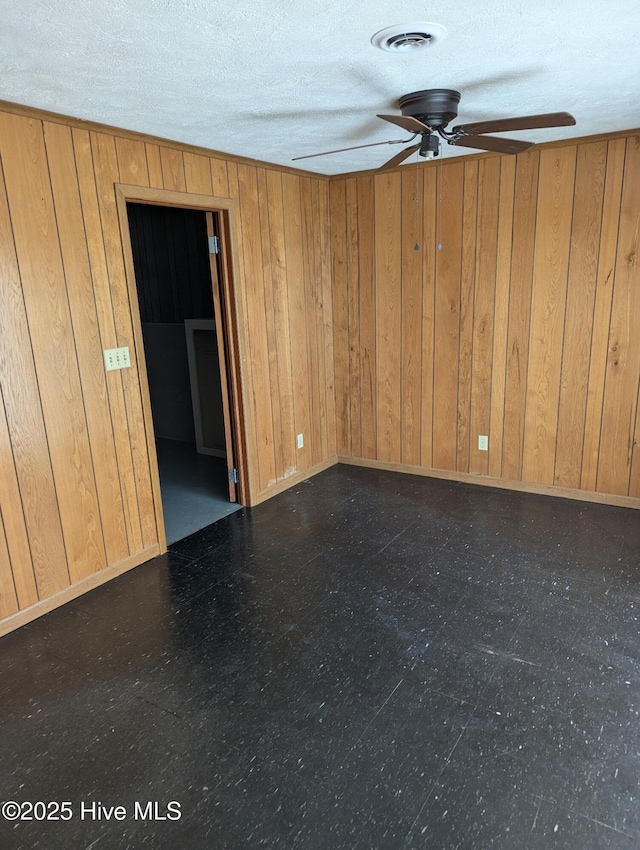 empty room featuring ceiling fan and wooden walls