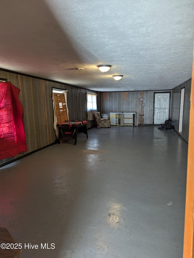 basement featuring a textured ceiling and wood walls