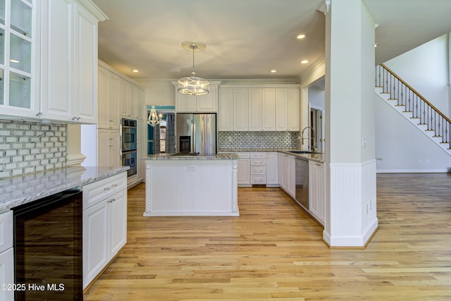 kitchen with light stone countertops, beverage cooler, white cabinetry, stainless steel appliances, and sink