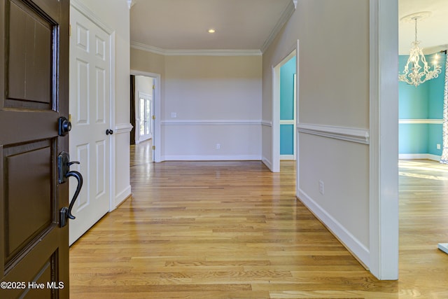 hall with light hardwood / wood-style floors, crown molding, and a notable chandelier