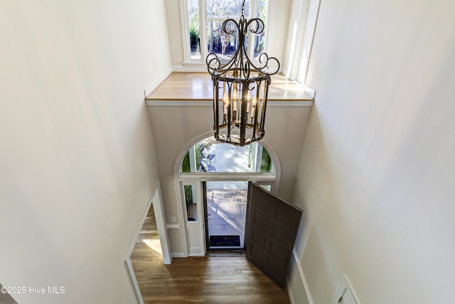 entryway with hardwood / wood-style floors, a high ceiling, and a notable chandelier