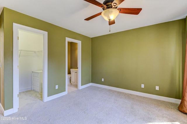 unfurnished bedroom with ceiling fan, connected bathroom, light carpet, a walk in closet, and a closet