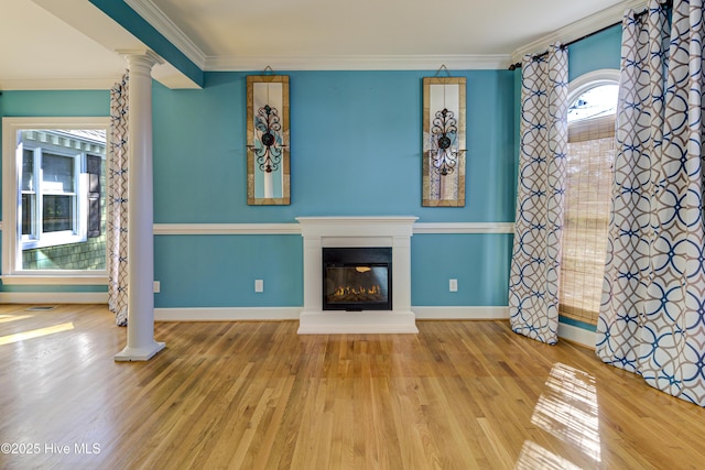 unfurnished living room featuring hardwood / wood-style floors, ornamental molding, and ornate columns