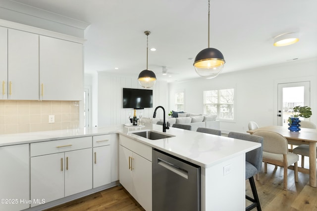 kitchen featuring stainless steel dishwasher, kitchen peninsula, sink, and white cabinets