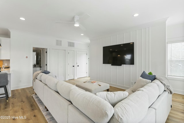 living room with crown molding, light hardwood / wood-style flooring, and ceiling fan