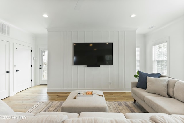 living room with crown molding and light wood-type flooring