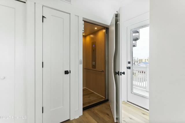 doorway with elevator and light wood-type flooring