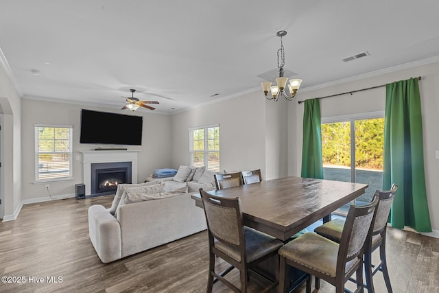 dining area featuring ceiling fan with notable chandelier, wood-type flooring, and ornamental molding