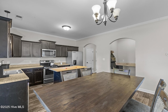 kitchen featuring crown molding, a chandelier, decorative light fixtures, stainless steel appliances, and dark hardwood / wood-style floors