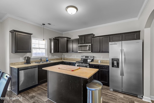 kitchen with sink, appliances with stainless steel finishes, crown molding, and a kitchen island