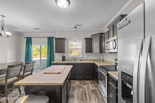 kitchen with sink, a center island, hanging light fixtures, and appliances with stainless steel finishes