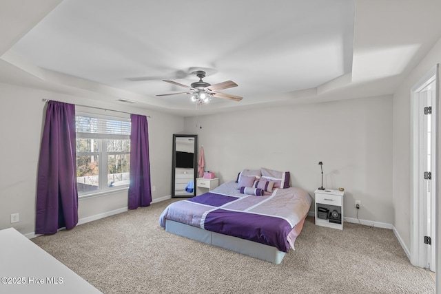 bedroom featuring ceiling fan, carpet flooring, and a tray ceiling