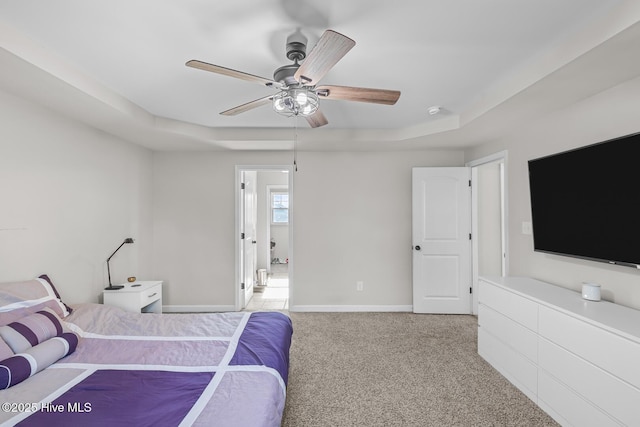 bedroom with light carpet, ceiling fan, and a raised ceiling