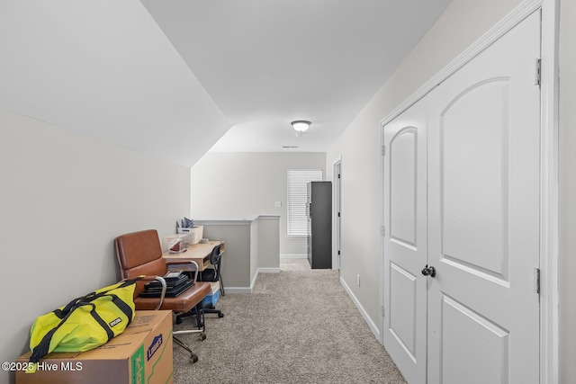 carpeted home office featuring vaulted ceiling