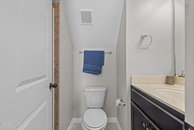 bathroom featuring toilet, vanity, and vaulted ceiling