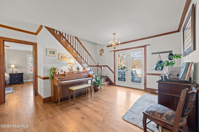 sitting room featuring french doors, light wood-type flooring, crown molding, and a notable chandelier