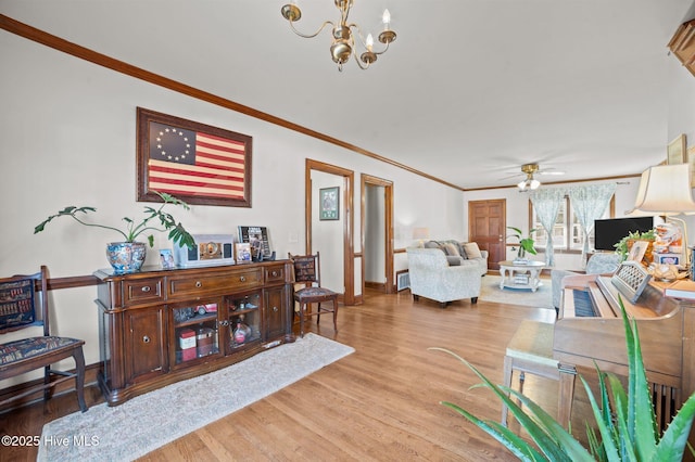 living room with hardwood / wood-style floors, ceiling fan with notable chandelier, and ornamental molding