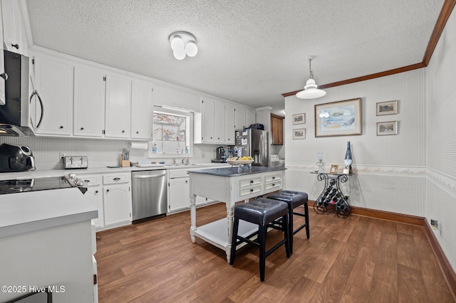 kitchen featuring dark hardwood / wood-style flooring, ornamental molding, stainless steel appliances, pendant lighting, and white cabinetry