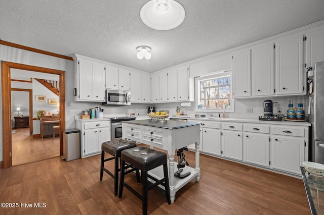 kitchen with appliances with stainless steel finishes, sink, white cabinetry, and wood-type flooring