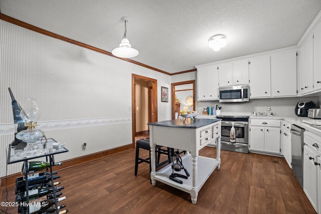 kitchen featuring ornamental molding, white cabinets, dark wood-type flooring, and appliances with stainless steel finishes