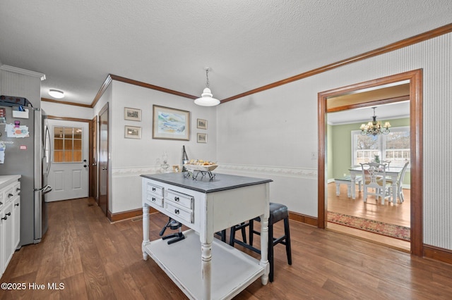 dining area with hardwood / wood-style floors, a notable chandelier, ornamental molding, and a textured ceiling