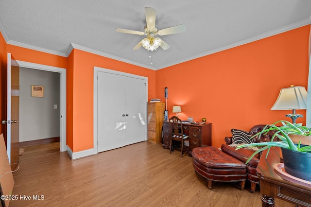 living area with a textured ceiling, ceiling fan, light wood-type flooring, and ornamental molding