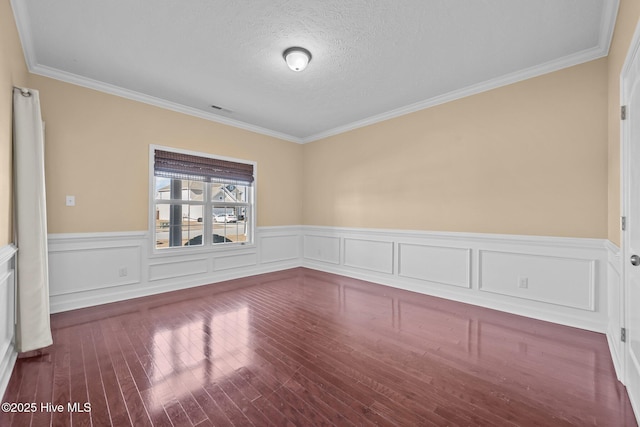 spare room featuring crown molding, hardwood / wood-style flooring, and a textured ceiling