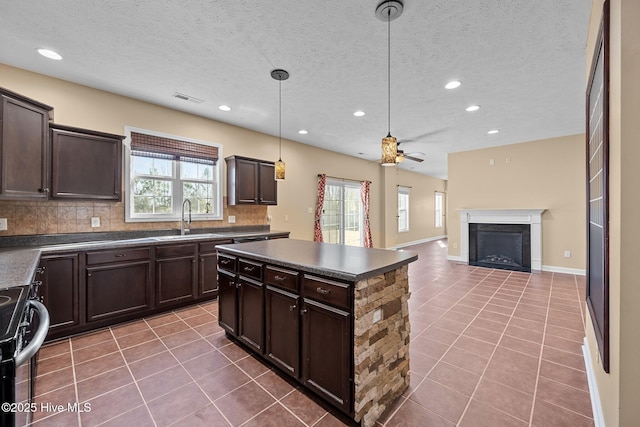 kitchen featuring sink, stainless steel range with electric cooktop, decorative light fixtures, dark brown cabinets, and tile patterned flooring