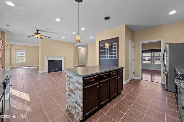 kitchen featuring pendant lighting, dark brown cabinetry, appliances with stainless steel finishes, and dark tile patterned flooring