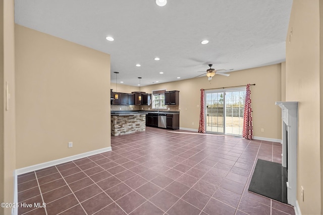 unfurnished living room with ceiling fan, dark tile patterned flooring, and sink