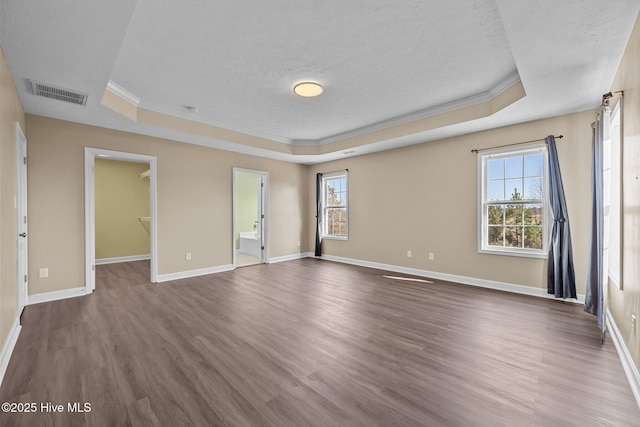 spare room with crown molding, dark hardwood / wood-style floors, a raised ceiling, and a textured ceiling