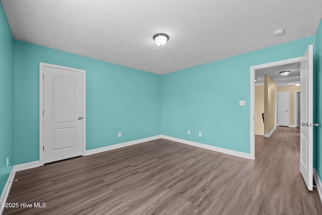 unfurnished room with hardwood / wood-style flooring and a textured ceiling