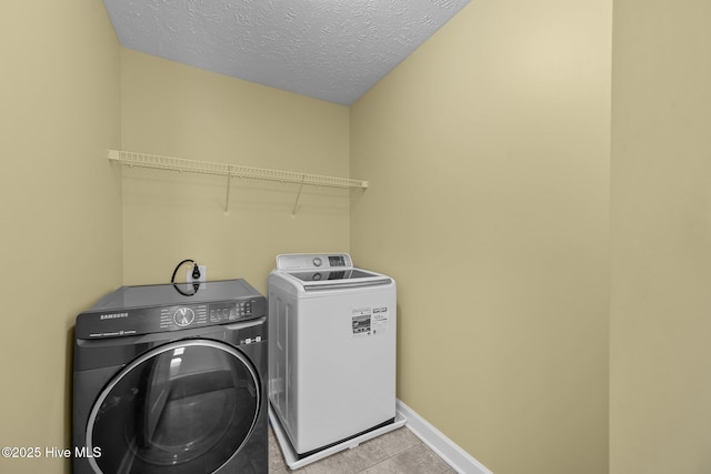 washroom with light tile patterned floors, a textured ceiling, and independent washer and dryer