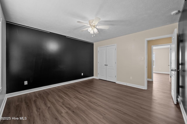 unfurnished bedroom featuring ceiling fan, dark hardwood / wood-style flooring, a closet, and a textured ceiling