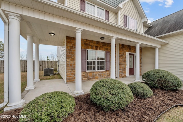 view of exterior entry with a porch and central AC