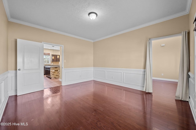 unfurnished room featuring hardwood / wood-style floors, ornamental molding, and a textured ceiling