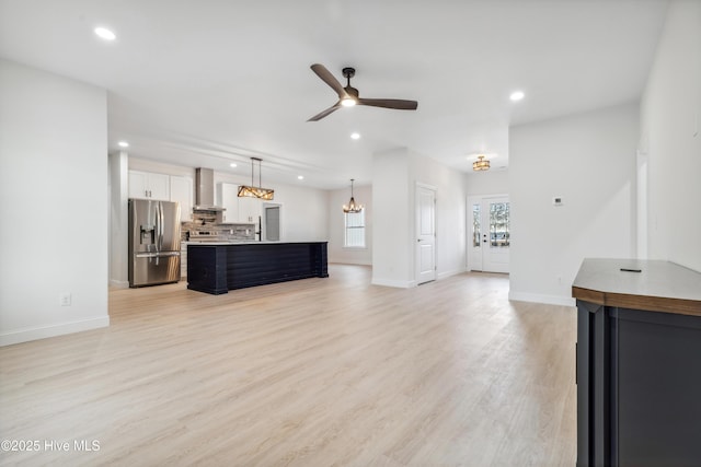 living room featuring ceiling fan with notable chandelier and light hardwood / wood-style floors