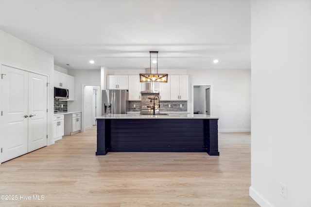 kitchen featuring white cabinetry, appliances with stainless steel finishes, a kitchen island with sink, and pendant lighting