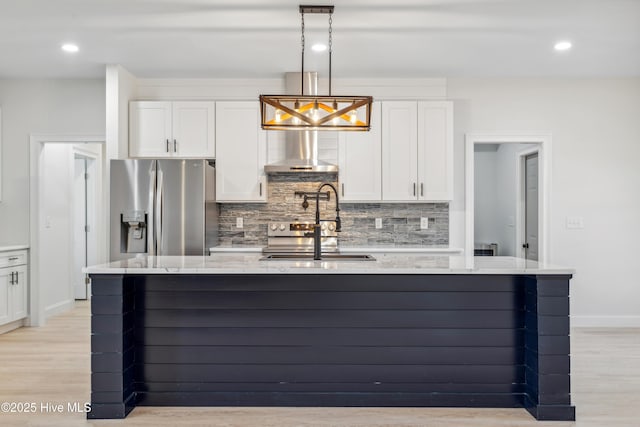 kitchen featuring white cabinetry, pendant lighting, stainless steel fridge, and wall chimney exhaust hood