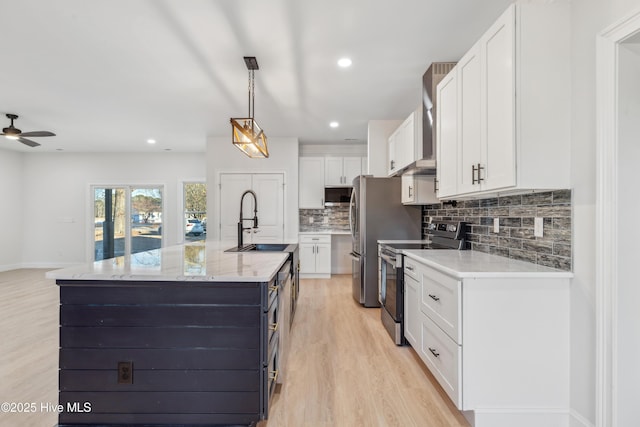 kitchen featuring decorative light fixtures, an island with sink, white cabinetry, sink, and stainless steel appliances