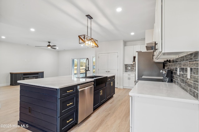 kitchen featuring pendant lighting, sink, a kitchen island with sink, white cabinets, and stainless steel dishwasher