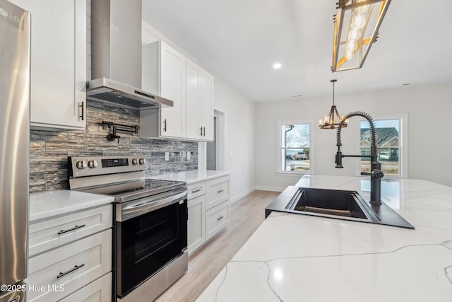 kitchen with wall chimney range hood, sink, stainless steel appliances, tasteful backsplash, and white cabinets