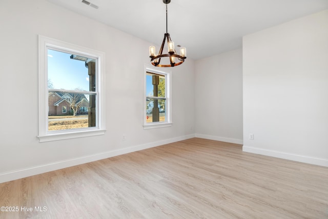 unfurnished room with a chandelier and light wood-type flooring