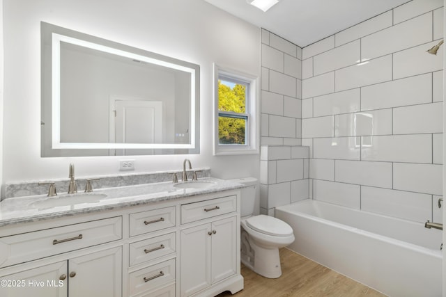 full bathroom featuring tiled shower / bath, wood-type flooring, toilet, and vanity