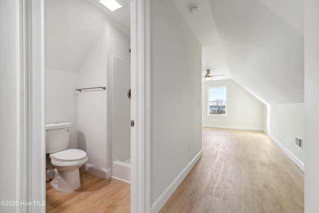 bathroom with hardwood / wood-style flooring, ceiling fan, toilet, and vaulted ceiling