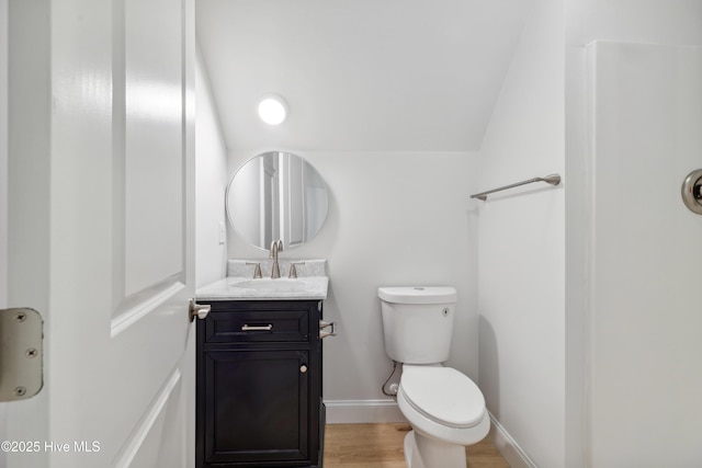 bathroom featuring vanity, vaulted ceiling, wood-type flooring, and toilet