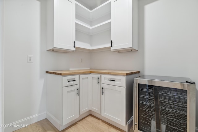 kitchen with white cabinetry, butcher block counters, and beverage cooler